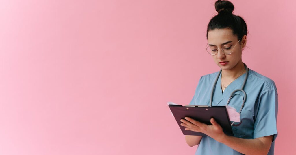 Professional nurse reviewing patient notes on clipboard with pink background, in studio setup.